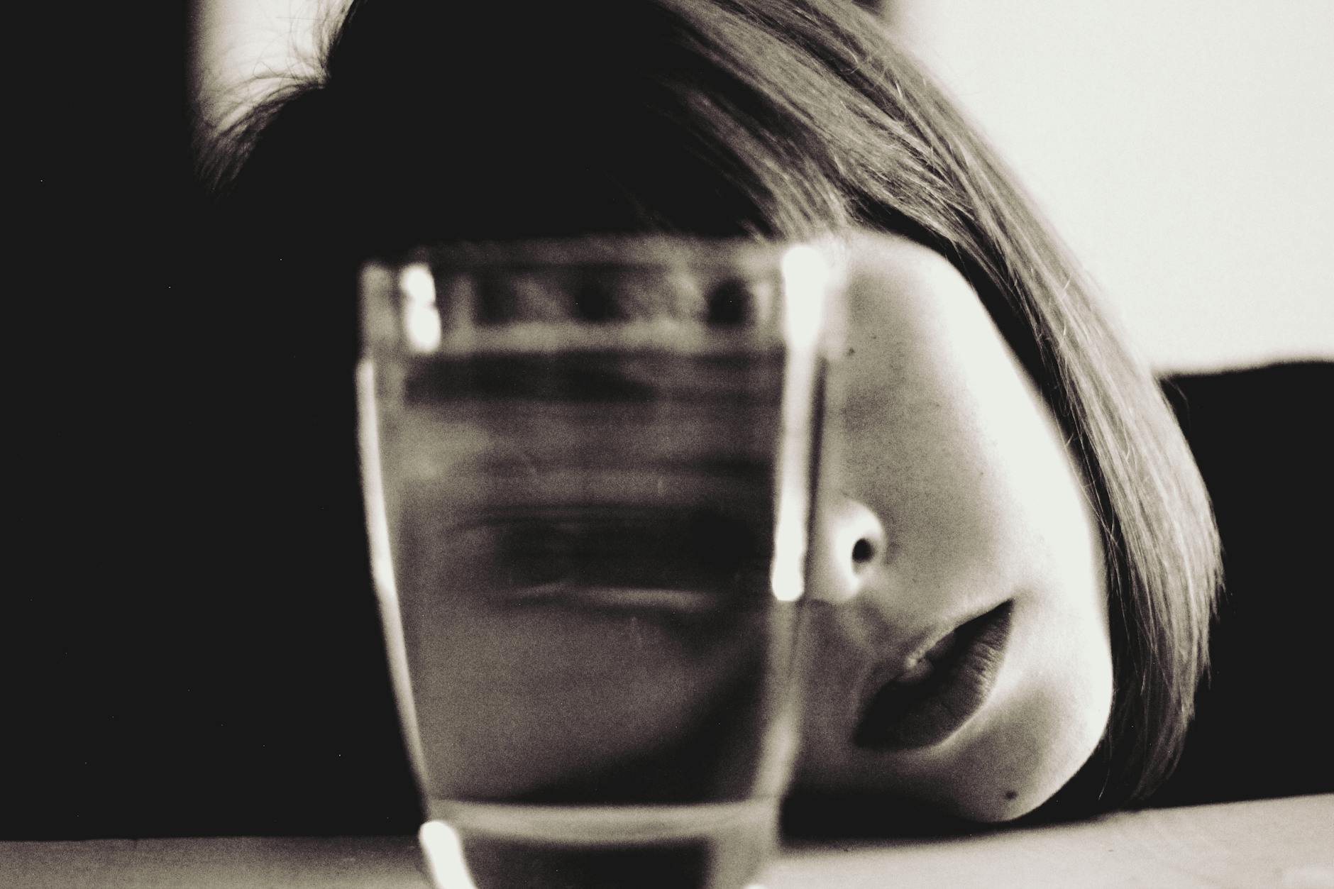 woman looking through a full glass of water